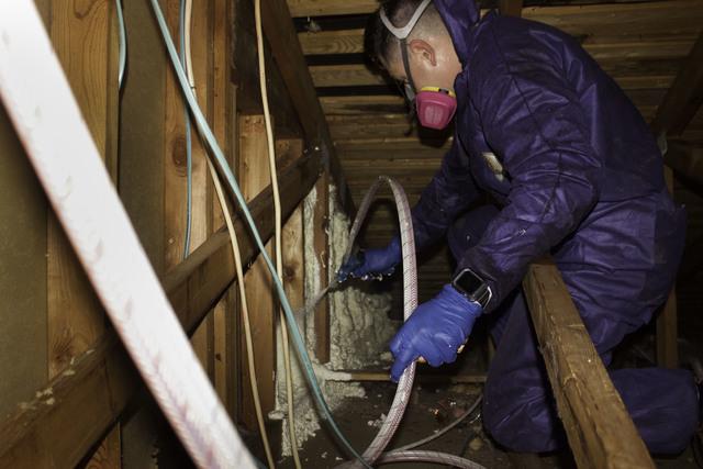 Ruben using spray foam in an attic