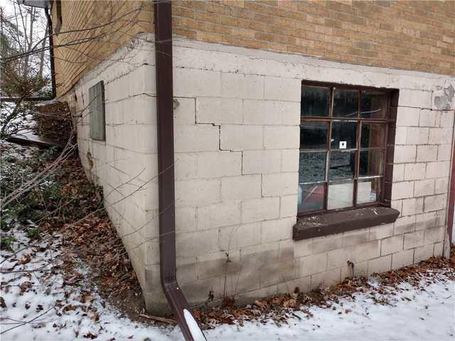 The tell-tale stairstep cracks in this block wall foundation point to pressure throwing it off-kilter. When the slab below shifts or sinks, the walls are left unstable while still trying to support the weight of the garage above. This stress causes fractures like the one seen here.