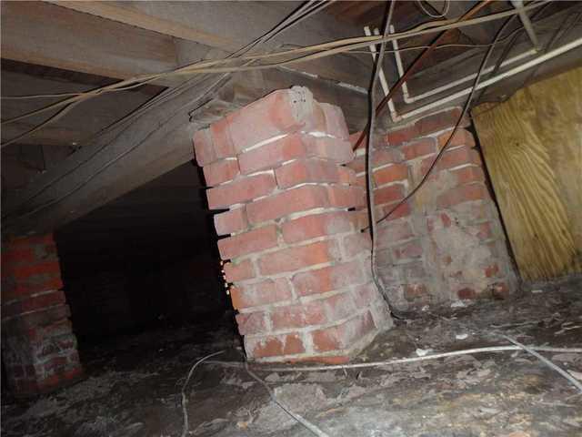 The old brick piers supporting the subfloor had sunk, causing the floor to buckle and the house to become unstable.