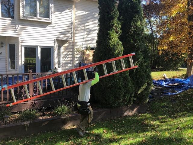 <p>Moving a ladder around the house to install toe boards on the edges of the roof to keep our employees safe.</p>