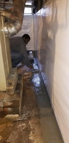 In this photo, Assistant Foreman Larry Foster is seen smoothing the cement which covers the top of the WaterGuard piping system.