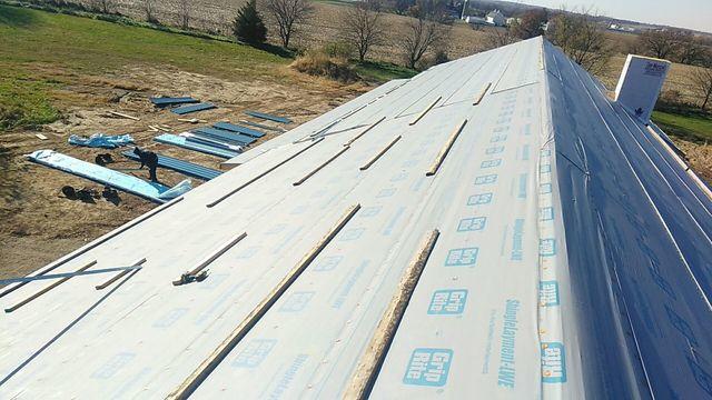 <p>View of the front roof slope before we install the new metal roof. On the ground you will see the light blue panels are organized and ready to be installed.</p>