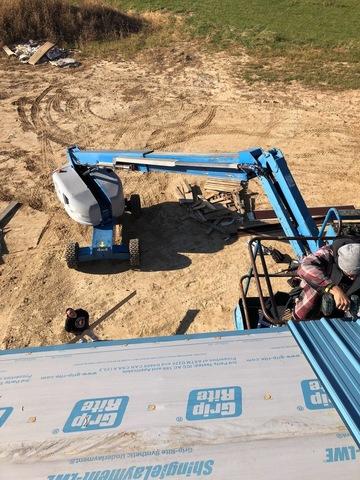 <p>Using a boom lift to fasten the roof panels on the edges was a safer way than using a ladder. The roof panels need to over hang 1-2" past the fascia board. A ladder 32' high would of been in the way. </p>
