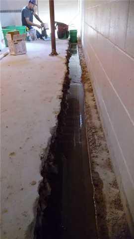 The WaterGuard installation process starts when the concrete is removed at the base of the walls, exposing the homes footing. As we can see in this picture, Amy's basement is in desperate need of WaterGuard, the trough we have dug to install the WaterGuard is already filling up with water.