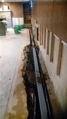 Once the concrete is removed at the base of the walls, the WaterGuard drain system can be set into place. Then drainage stone is laid around the WaterGuard to allow maximum drainage.