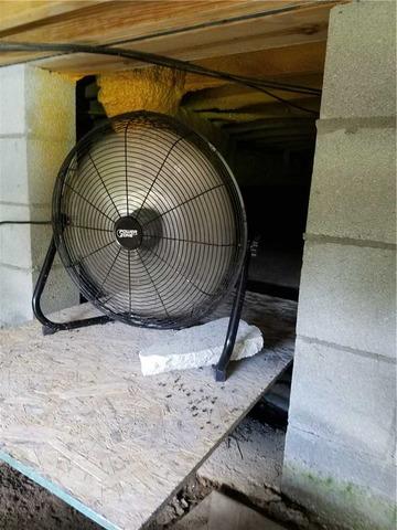 A fan blows warm, humid air into the cool crawl space, making the existing problems worse