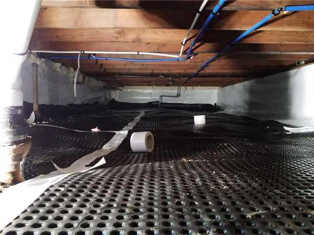 Encapsulating a wet crawl space can cause problems, as the CleanSpace sticks to the ground and doesn't let water flow to the sump pump. By installing dimpled drainage matting first, we create just enough space for easy movement.