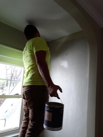 Painter Romulo is making sure this line between the ceiling and wall color is kept clean as he paints.