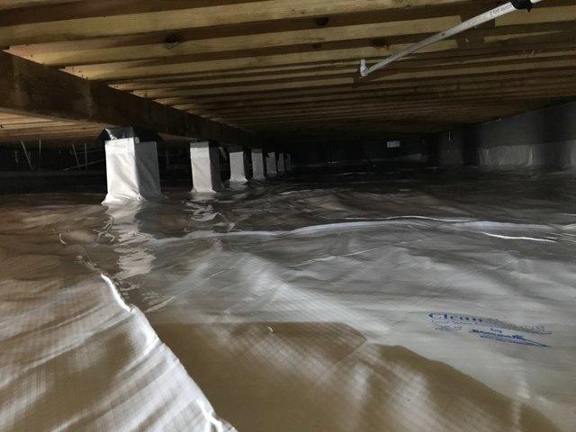 The CleanSpace vapor barrier is installed. All seams are overlapped and sealed, the liner is fastened to the walls 6-8 inches above outside grade, and it is wrapped and sealed around all piers. This completely seals the crawl space off from the earth's moisture.