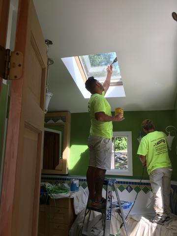 The skylight is painted while another painter gives the wall a fresh coat.