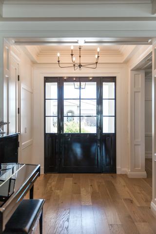 As you enter the home through the custom front door, you are greeted by custom coffered ceilings and wainscoting throughout the home.