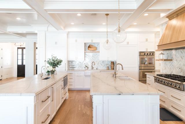 This client expressed her vision for two islands in this very customized kitchen with beautiful white stone countertops, clean white cabinet design and custom hood.