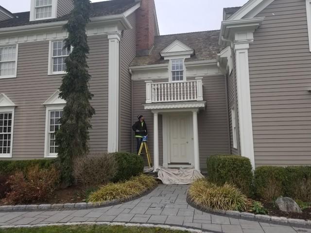 A painter applies new paint to the side door and columns.