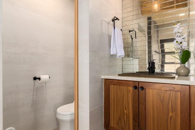 The bathroom has barn door on the inside. The walls are a continuation of the Angela Harris Inspira Light Silver 24x48 Porcelain Tile that is in the dressing room. The countertop is Taj Mahal Quartzite.