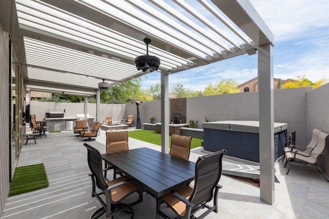 Really, it's like a resort back here. You have the hot tub, the grills, the fire pit, plenty of tables and chairs and a very beautiful, comfortable space to be. The louvered ceiling is open here.