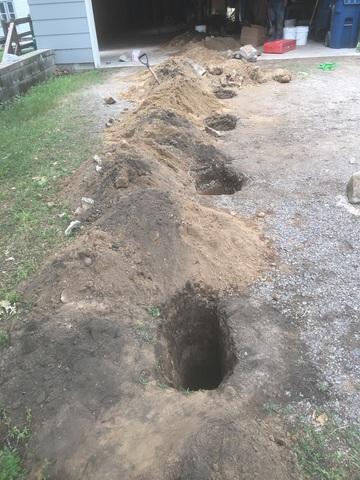 Our Foreman, Juan Pena, and his crew dug five holes in the gravel driveway to begin the GeoLock Wall Anchor installation.