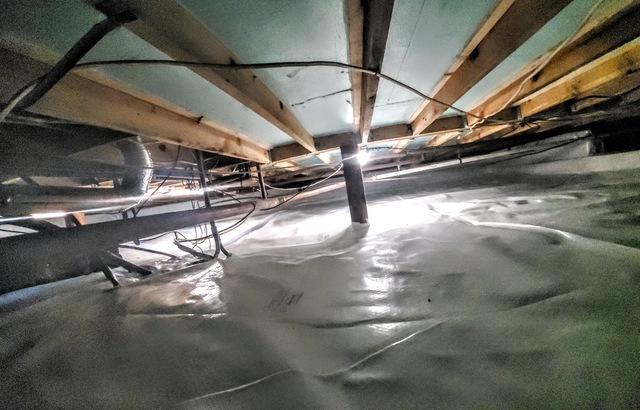 Wide shot of crawl space encapsulated from front to back in the first section of the crawl space with insulation in the floor joists.