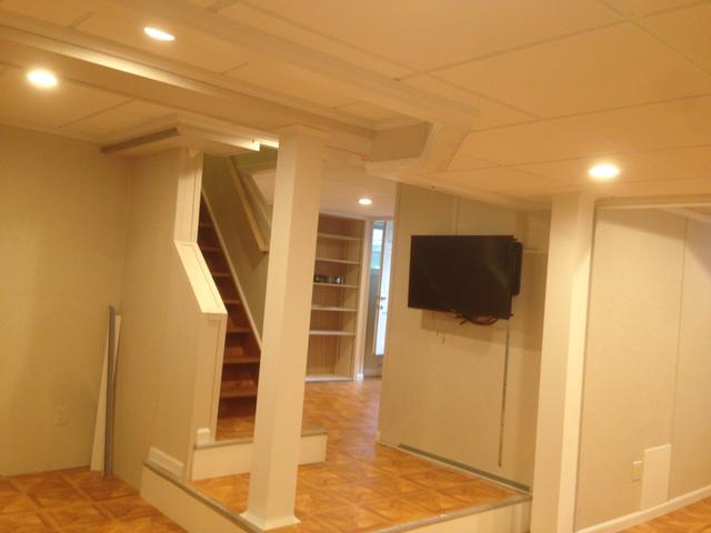 After picture of the carpet ready staircase with built in shelving in the background. (TV not included in Total Basement Finishing Systems!) 