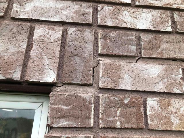 Cracks along the bricks of a home, as well as the window crack as well