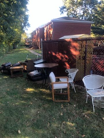<p>Items left by the dumpster including chairs a table, end table and other miscellaneous items. </p>