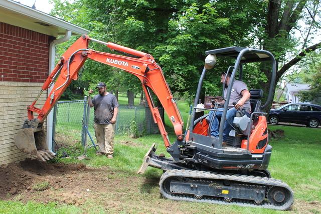 Foundation crew backfilling the dirt where the helical piers were installed to stabilize the home