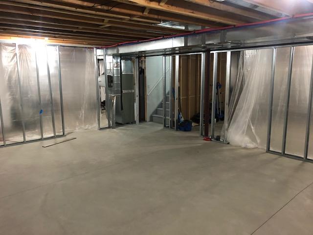 <p>Early in the installation process, you can see the framework for the EverLast Wall Panels has been installed around the exterior of the finished area of the basement as well as to divide the basement into finished and unfinished halves. Plastic protects the areas not being worked on.</p>