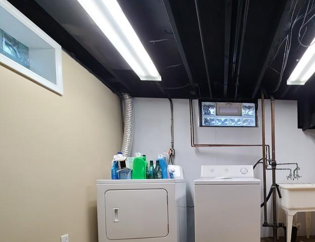 The basement ceiling has been painted black and the lights reinstalled. Even though it is dark it looks clean and adds depth to the space.