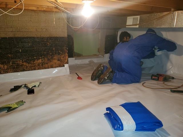 One of our production crew members installs more CleanSpace liner to the crawl space walls.