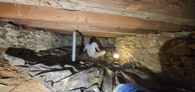 A 3 Pros Basement Systems production crew member starts to clean up the old materials in the crawl space.