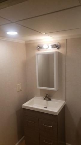 The homeowner provided the mirror, but the lights and vanity are standard to our remodels. Our EverLast Wall Panels are easy to hang things from and work well in all rooms of a basement, including the bathroom.