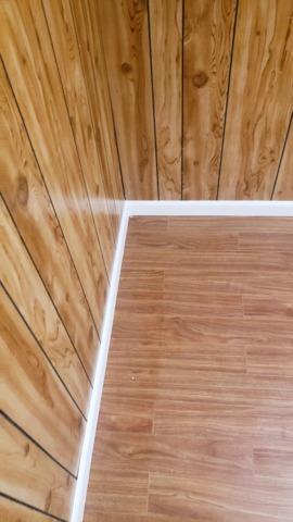 The Thermal Dry Elite Plank Floors meet up with the homeowner's older wood paneling in this photo. The trim at the bottom of the wall breaks up the wood tones.