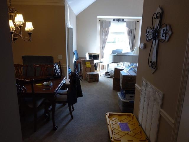 The dining room table and chairs are in place, the china hutch is in place, and the baby grand piano are in place. There are also a number of other pieces of furniture, boxes, and other things moved in to these rooms, based on where they expect to be used once they are unpacked.