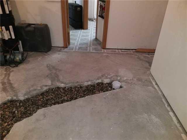 This is the WaterGuard port that extends beyond the perimeter to the middle of the floor where all the cracks are. The line that connects it to the WaterGuard is under the rocks but the white part sticking up will not be covered once the concrete is restored. This is where water that starts to pool gets collected and sent to the sump pump.