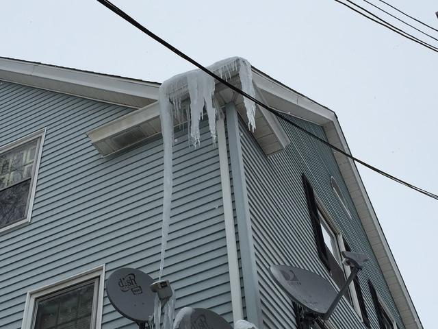 <p>The icicles hanging from this roof are so big they are touching the satellite dish! Big icicles like this can cause severe damage to the exterior of your home and lead to physical injury from falling ice.</p>