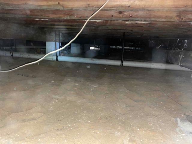 The dirt floor of this vented crawl space is uncovered, allowing moisture to rise from the earth and into the space. This can affect the environment and raise relative humidity, which can lead to mold growth, higher energy bills, and moisture damage in the crawl space.