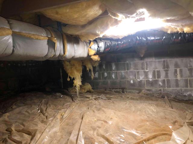 The block foundation walls are porous allowing moisture from outside to seep through. The white substance you see on the block wall is efflorescence, it is a result of minerals being pulled to the surface of the block as water works its way from the wet ground outside of the crawl space, through the block, and under the home.