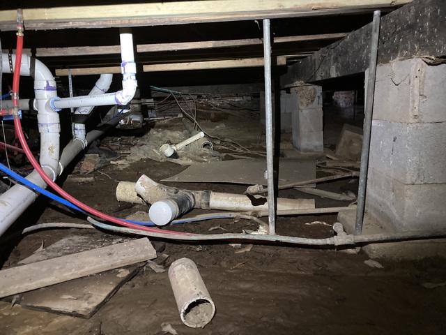 Before our crew cleaned out the crawlspace. You can see how wet the mud is in this photo. If you look towards the middle back you can see remnants of plastic sheeting that was put down to be a moisture barrier.