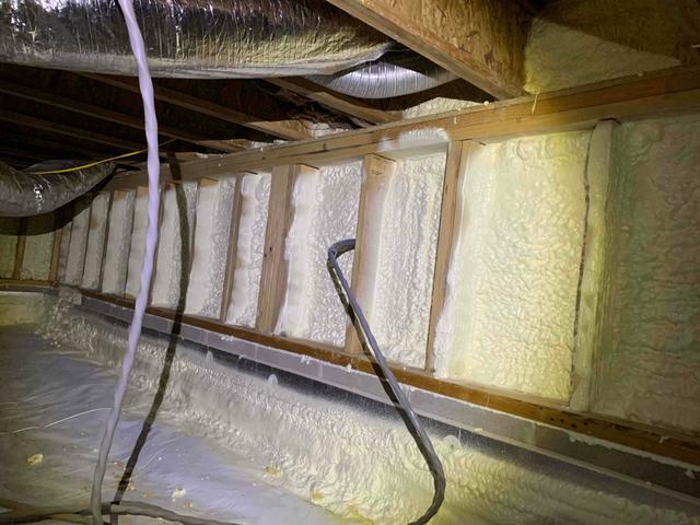 An inch and a half thick coat of closed-cell spray foam was applied over the foundation walls of the crawl space. At an R-10 value, this spray foam not only insulates the crawl space but acts as an air barrier and vapor retarder. The open vents lining these walls are also internally blocked off and sprayed over, shutting off the flow of infiltrating air and moisture.