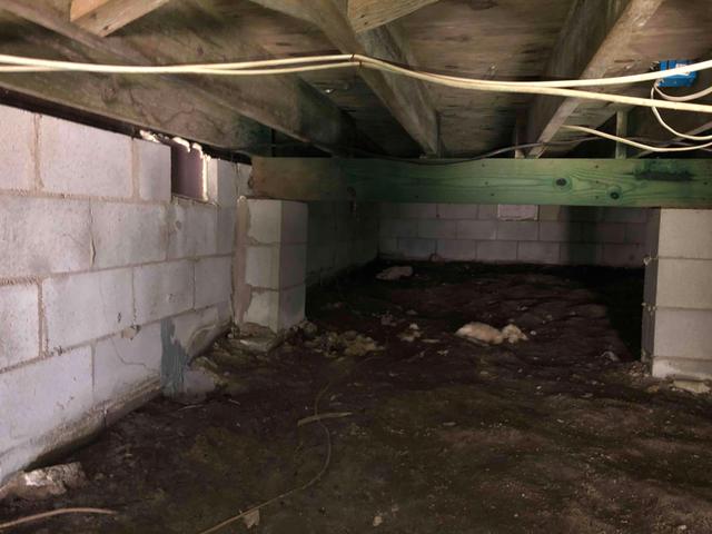 The dirt flooring of this crawl space remains exposed, allowing the earth's moisture to rise into the crawl space and affect the relative humidity and environment. Excessive moisture can lead to condensation, mold growth, and moisture damage to materials. This muddy and damp environment also makes it difficult for service persons to maneuver around the crawl space.