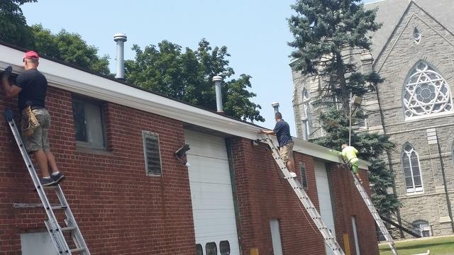 4 people holding 145 ft gutter while it was being installed