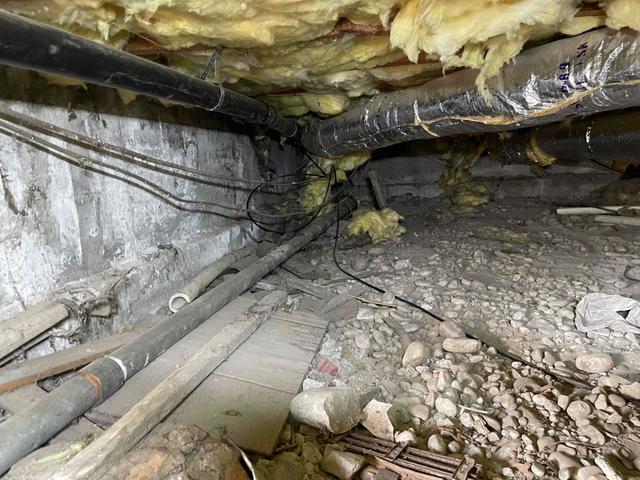 Workers examine the crawl space to see what the current state is before cleaning.