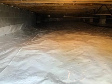 We installed a durable 10-mil vapor barrier, called CleanSpace Light, over the dirt floors of this crawl space. This 7-layer polyethylene liner is wrapped around all piers, sealed with vinyl tape, and mechanically fastened to the foundation walls six to eight inches above outside grade, giving the crawl space better protection from the earth's moisture.