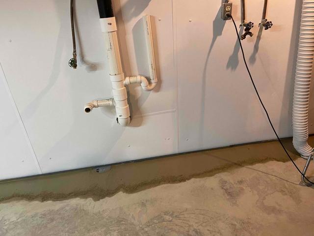 A WaterGuard floor drainage system installed to redirect water leaking through the basement wall and floor to a TripleSafe sump pump