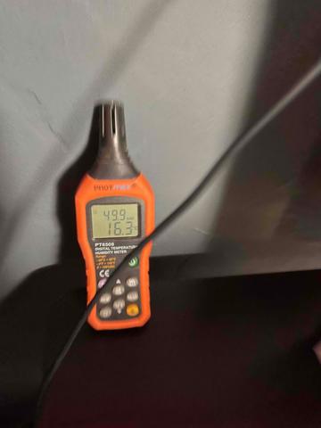 The foreman uses a temperature sensor to check the humidity and temperature state of the crawl space.