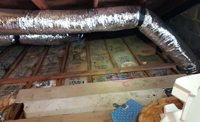 Looking in the attic we see old insulation and moisture that has stained the fiberglass insulation.