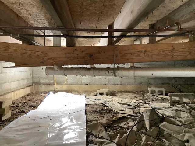 We began our project by installing 106 linear feet of drain tile around perimeter of crawlspace and tied into a SuperSump with a Zoeller M98 sump pump. We discharged that plumbing to the outside through an IceGuard that runs to a 15 foot underground downspout. To combat the heavy areas of mold, we sprayed Mold-X.

To help manage moisture and humidity, we installed a CleanSpace Encapsulation System over exterior walls, across the floor, and around existing pilasters. The encapsulation system was buttoned along the walls, with all seams on the walls and floor overlapped, then sealed with urethane, and secured with industrial tape. 

To help support the structure, we installed a new beam on existing support columns and pocket. We also sistered floor joists with new lumber. 

Finally, we installed an AprilAire E100 and drained that into the SuperSump.