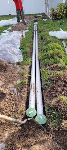 Hard pipe is installed into the ground and connected to pop up drains, the only item that is visible once this project is complete. The pipe allows the excess water to flow easily out into the street rather than pool around this homeowner's foundation.