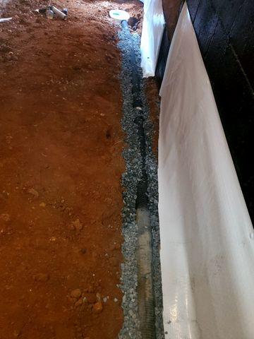 A drainage system was installed to collect invading water and pump it out of the crawl space.