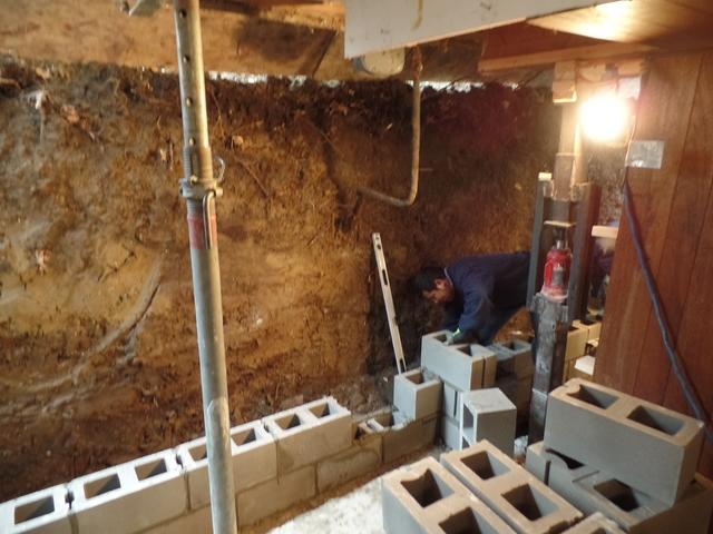 Building a new foundation wall is quite the process, in this photo they are laying the first course of block for the new wall. 