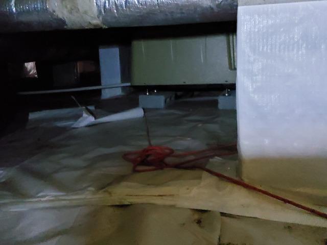 The vapor barrier was not properly sealed around the crawl space piers. In the background is the second of 3 failing dehumidifiers.